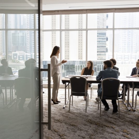 Wide,Shot,Of,Multiethnic,Business,Team,Talking,At,Meeting,Table